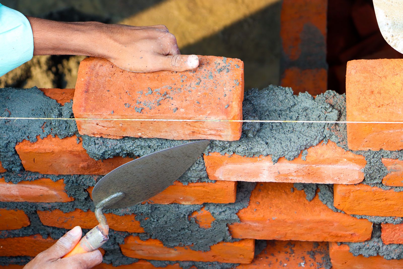 Bricklayer setting a face brick with a trowel