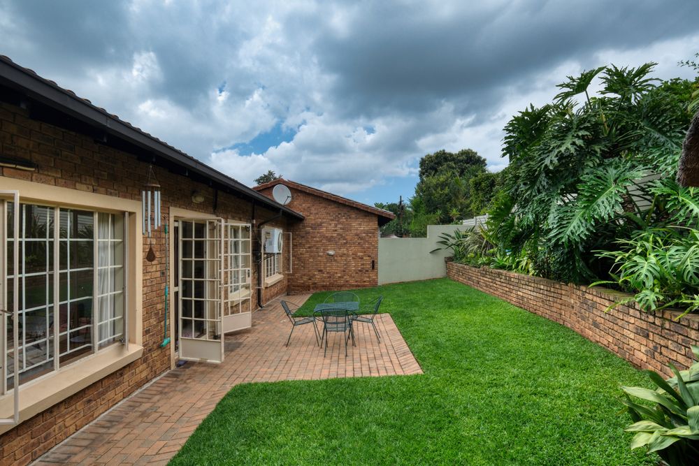 Brick paved patio beside a lawn and garden wall