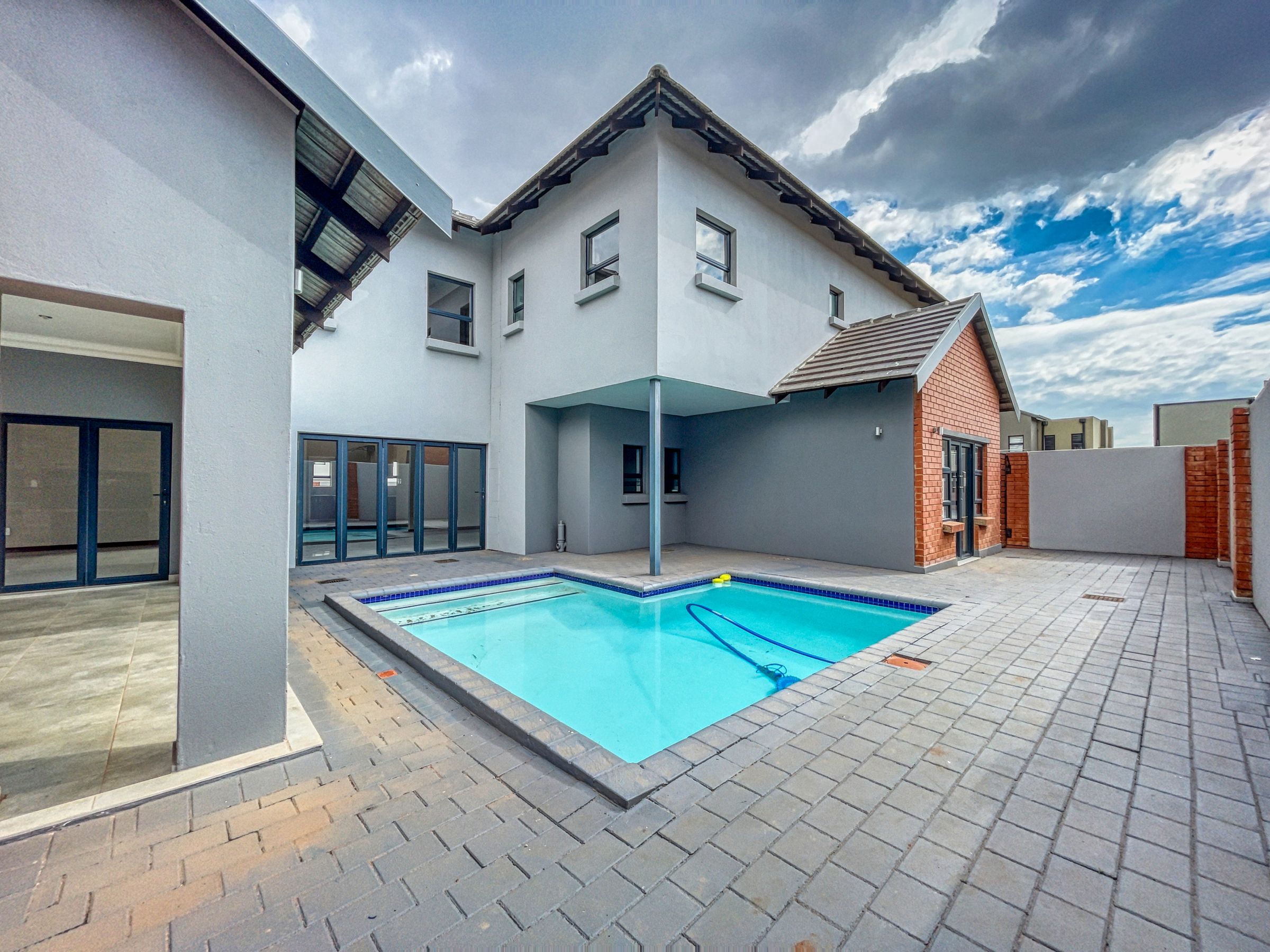 Grey block paved courtyard beside a swimming pool