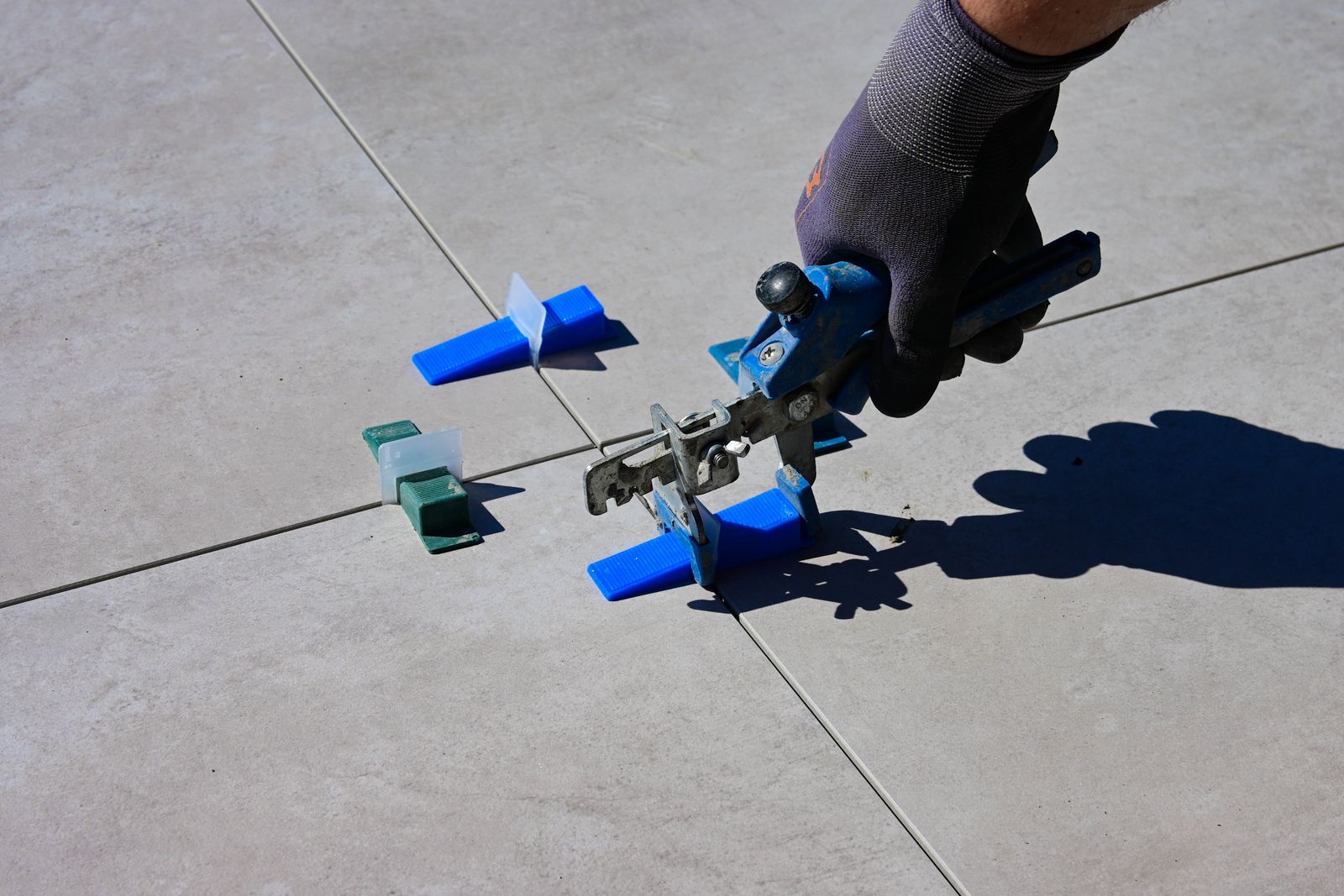 Gloved hand fitting a floor tile with levelling clips